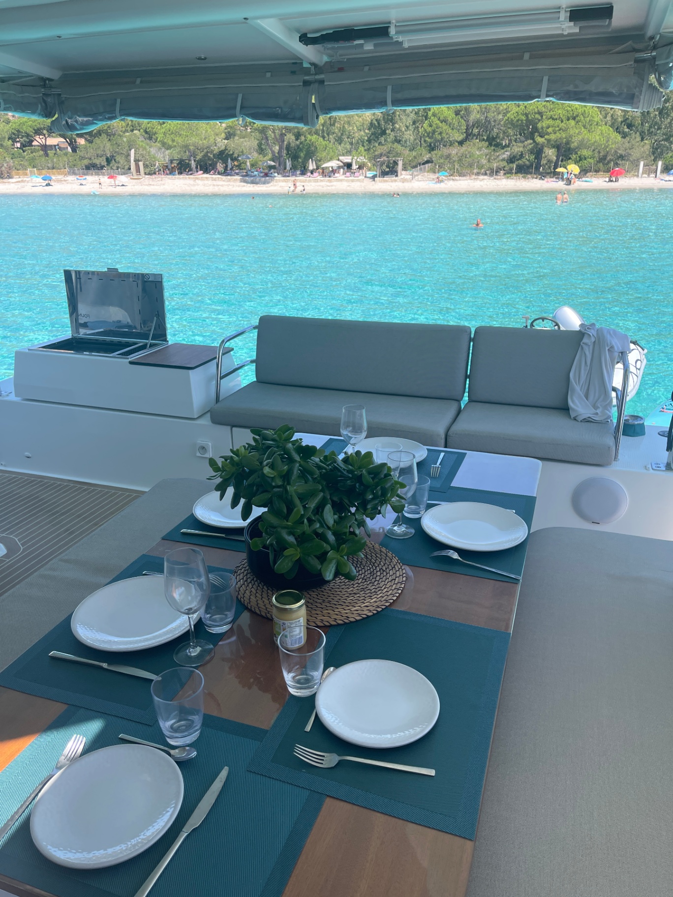 Shaded aft cockpit of HONU MOANA set for lunch with a beach view
