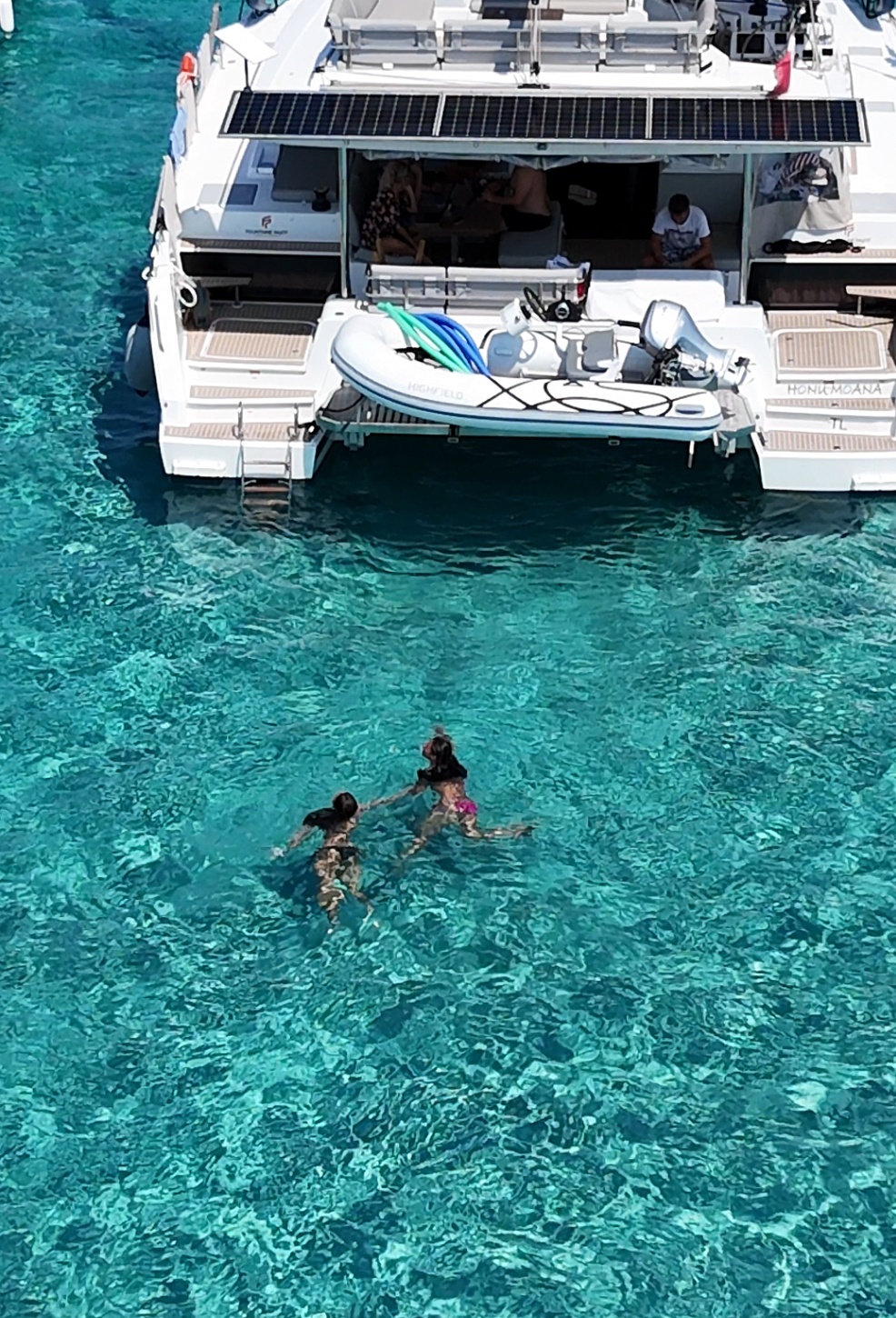 Guests swimming beside HONU MOANA's transom and tender in shallow Caribbean water